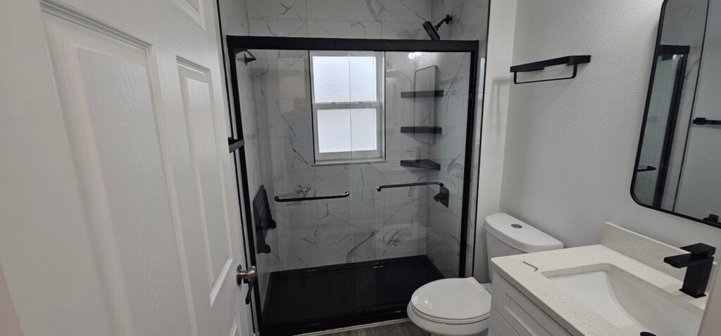 Finished accessible walk-in shower remodel with black framed glass enclosure, grab bars, tile walls, and updated bathroom fixtures near The Villages, Florida